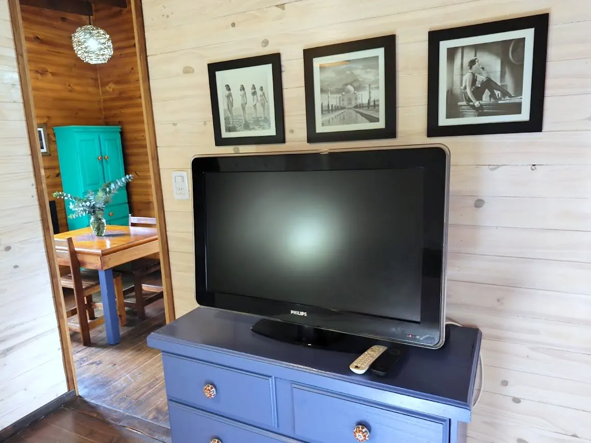 Dormitorio de la Cabaña Chuña 1 con TV y cómoda azul restaurada