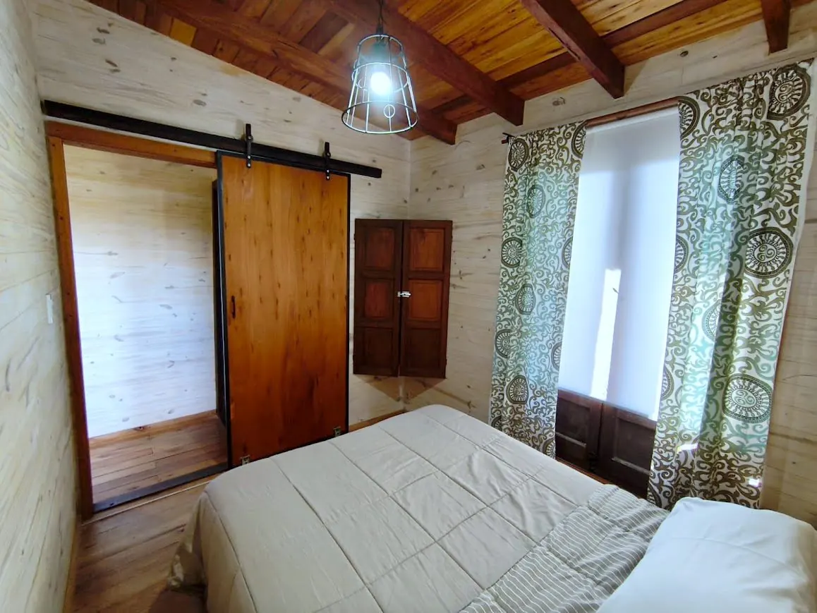 Dormitorio de la Cabaña Chuña 2 con puerta corrediza de madera y techo a la vista