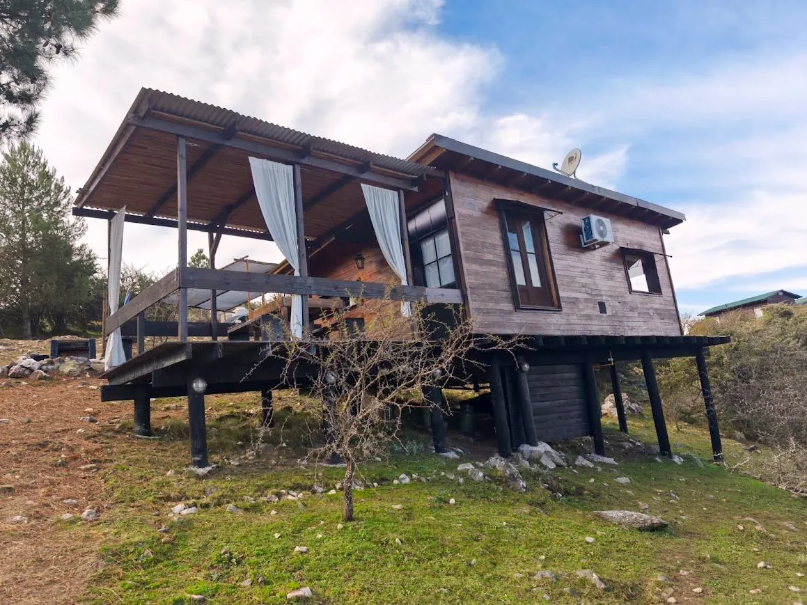 Cabaña Chuña 2 de madera sobre pilotes con galería y vista a las sierras en San Clemente, Córdoba