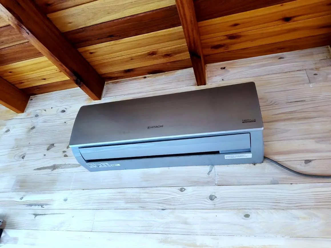 Aire acondicionado Hitachi bajo el techo de madera de la cabaña