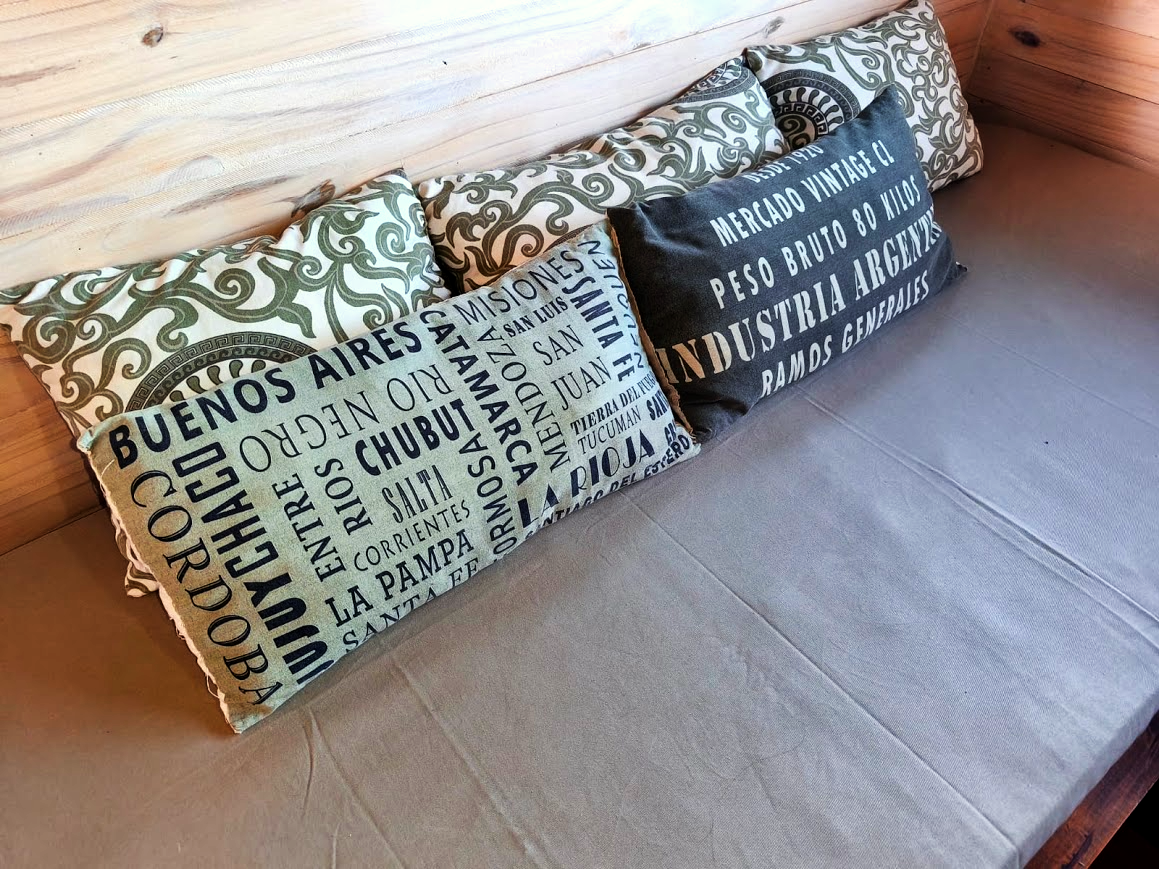 Almohadones estampados con nombres de provincias argentinas en el living de la cabaña
