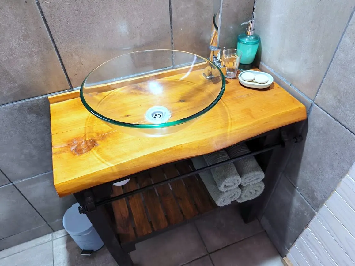 Bacha de vidrio sobre mesada de madera maciza en el baño de la cabaña