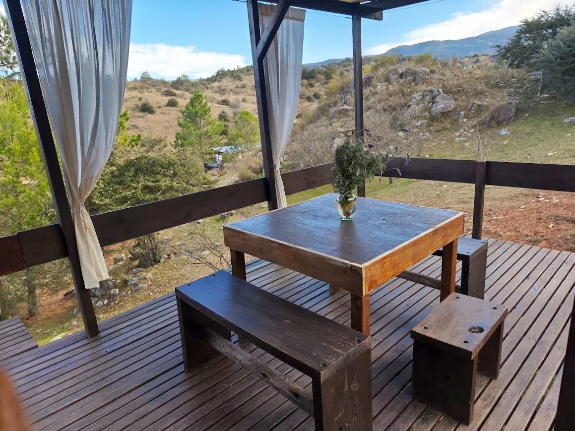Galería con mesa de madera y vista panorámica a las sierras de Córdoba